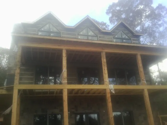 Dormers and porch framing on a large log home under construction — Roof Coating work by our crew in Lincroft