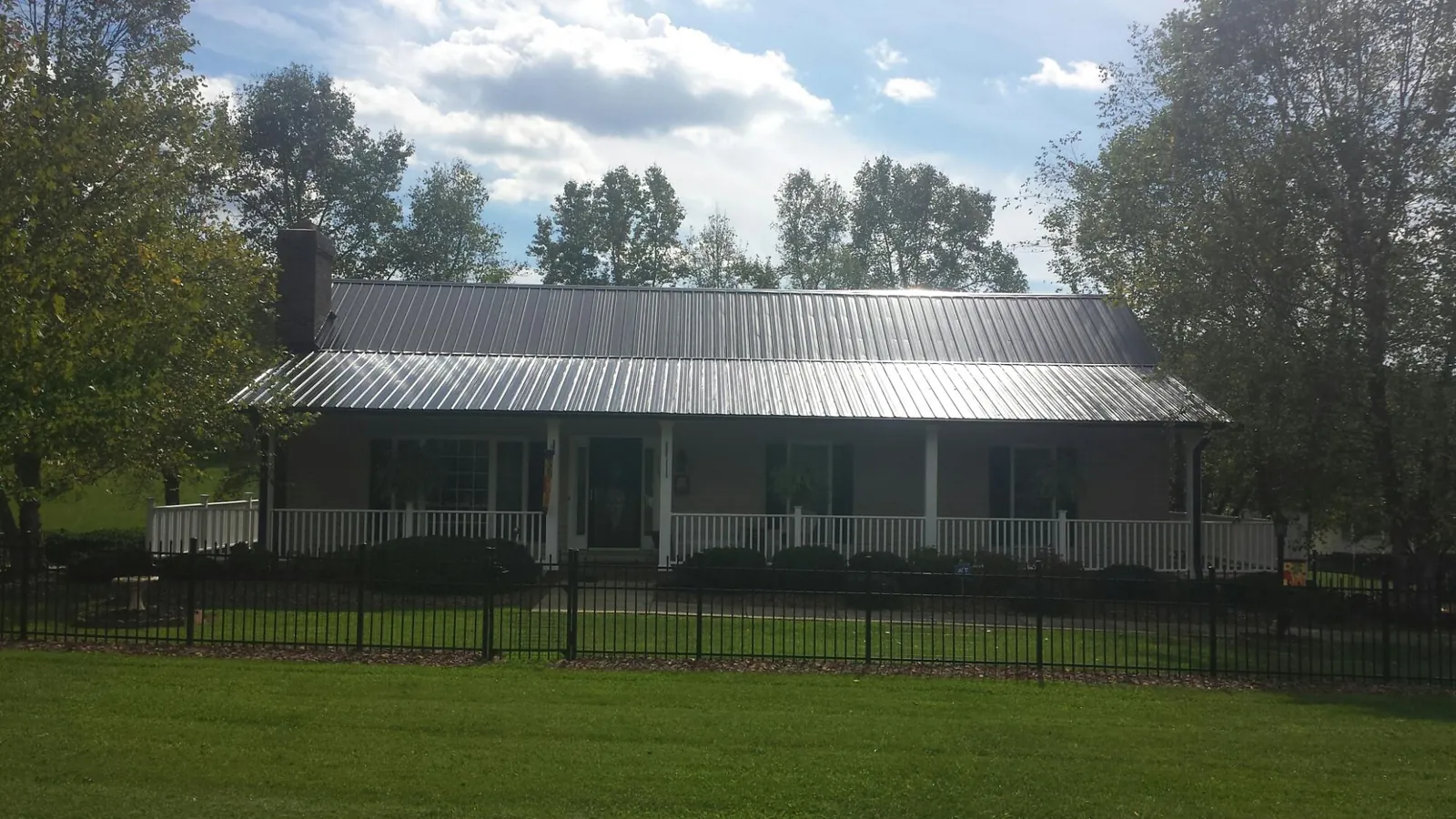 Gray metal roof on a brick ranch with a full width front porch — Gutter Guard Installation work by our crew in Lincroft
