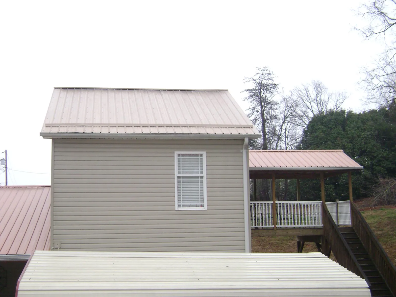 Tan metal roofs on a two story addition and attached porch, from a Roof Replacement job in Lincroft