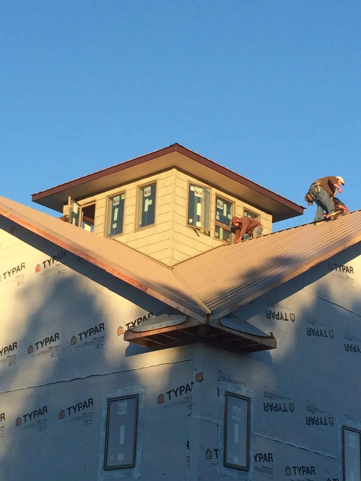 Roofers working around a rooftop cupola on a new metal roof at sunset — Roof Waterproofing in Lincroft by Roofing Brothers